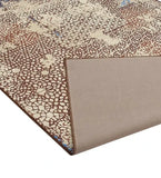 Close-up of luxurious distressed mosaic pattern rug with beige and brown tones, folded corner showing texture
