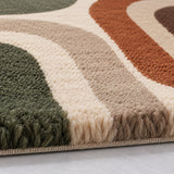 Close-up of a textured area rug with a retro wavy pattern in olive green, cream, beige, taupe, and terracotta, showing the pile texture and fringe detail.