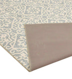 Gray geometric floral patterned luxury rug with folded corner showing solid beige backing