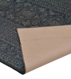Close-up of luxury dark gray ornate border rug with intricate floral patterns and folded corner showing beige backing