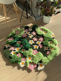 Hand-tufted green floral wool rug with sculpted moss texture and pink and white flowers