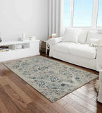 Ivory distressed Persian design rug with blue accents on wooden floor in bright living room with white sofa and cabinet