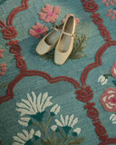 Handcrafted wool rug featuring classic floral arch design.