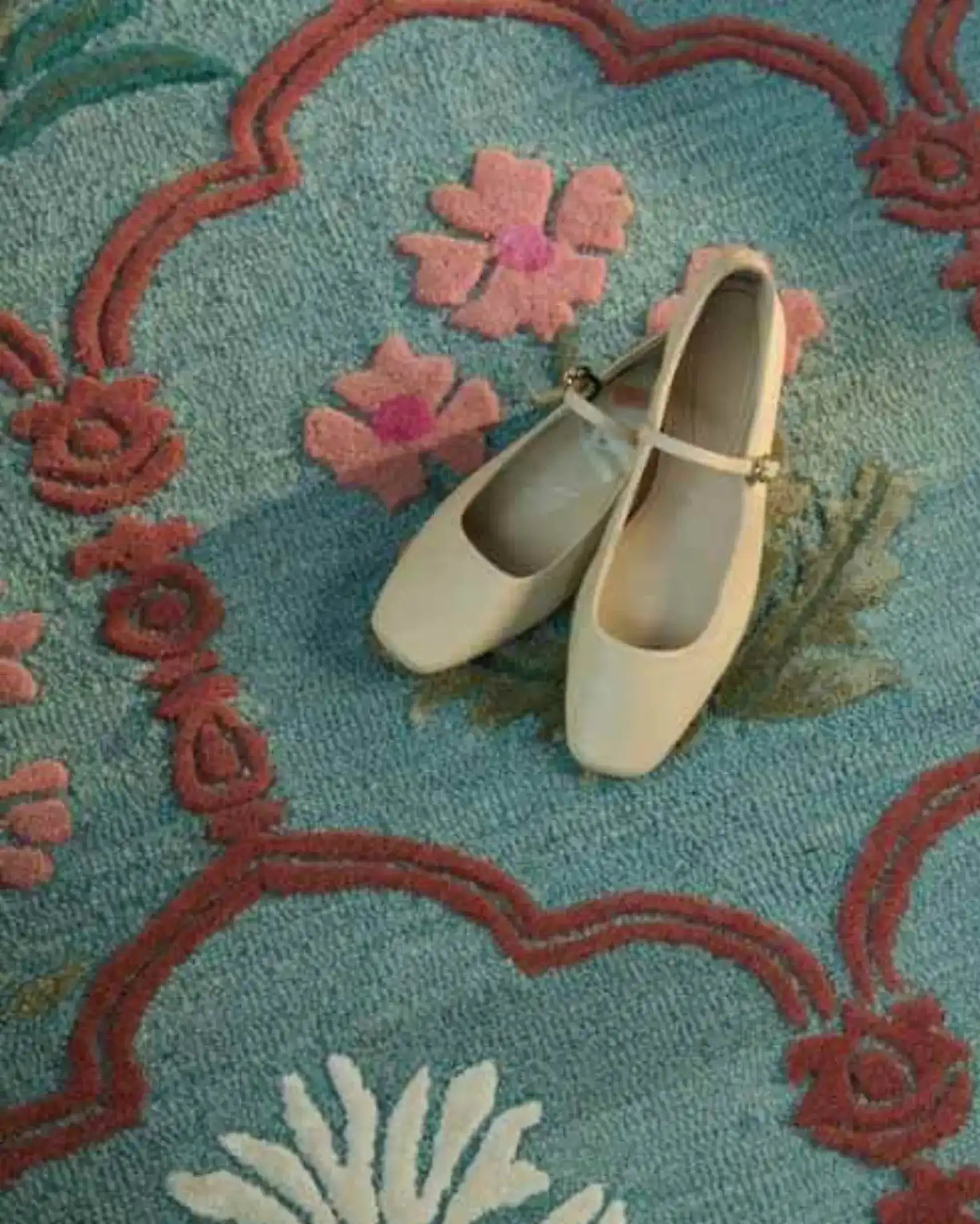 Traditional botanical rug in muted teal and red accents.