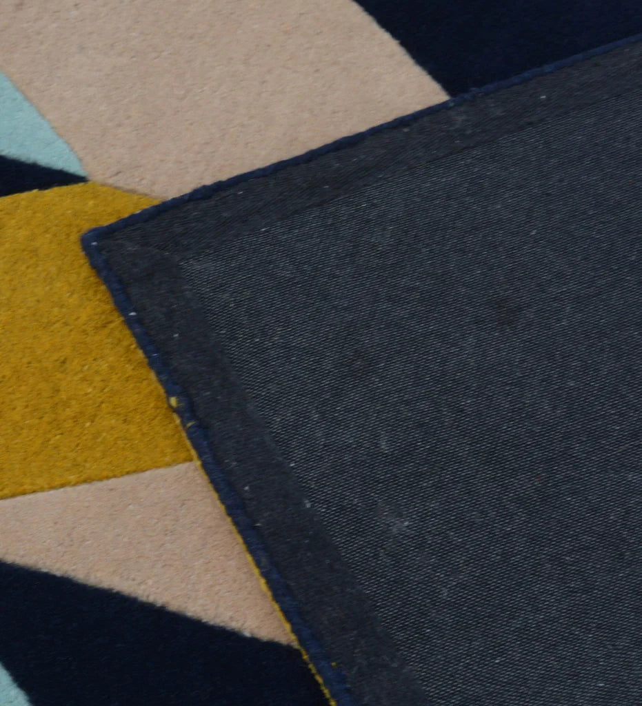 Modern multicolor hand-tufted rug with bold chevron pattern in mustard yellow, navy blue, blush pink, and sky blue.