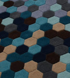 Close-up of modern geometric hexagon rug with gradient shades of blue, gray, brown, and beige
