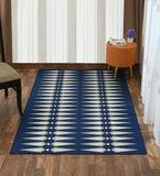 Modern geometric navy blue rug with white arrow patterns on wooden floor in stylish living room