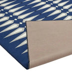 Blue and white geometric patterned modern luxury rug with folded corner showing beige backing
