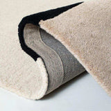 Close-up of layered luxury tufted area rugs in beige and black, showing textured pile and woven backing