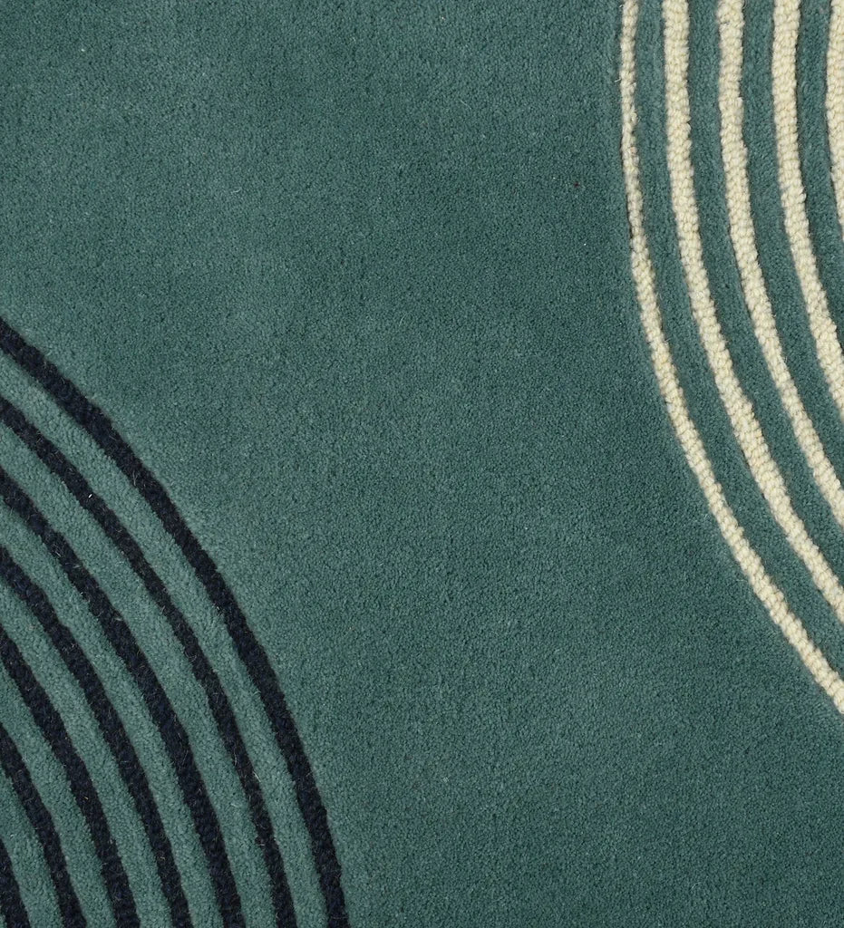 Close up of  Hand-tufted wool rug with colorful arched geometric lines in teal, mustard, black, and beige.
