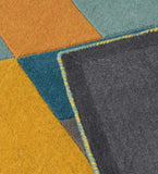 Multicolor geometric prism rug with mustard yellow, teal, and orange shapes, corner folded showing back