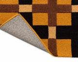 Close-up of a geometric patterned rug with brown, orange, and black squares.