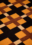 Geometric patterned rug with brown, orange, and beige squares on a black background