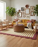Modern living room with mustard yellow striped scallop edge rug, mustard sofa, wicker chairs, and decorative wall art