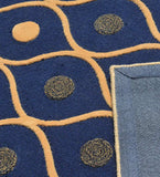 Navy blue rug with modern geometric orange lines and circular patterns, showing corner backing