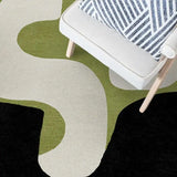 Modern abstract geometric rug in olive green, cream, and black under a white armchair with striped cushion