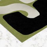 Olive green modern abstract geometric handwoven rug with black and cream shapes on marble floor