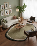 Olive green and beige irregular hand-tufted area rug styled in a living room, featuring organic shapes and earthy tones for a modern, natural accent