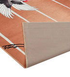 Peach-colored luxury area rug with white stripe accents and artistic black and white bird design, corner folded