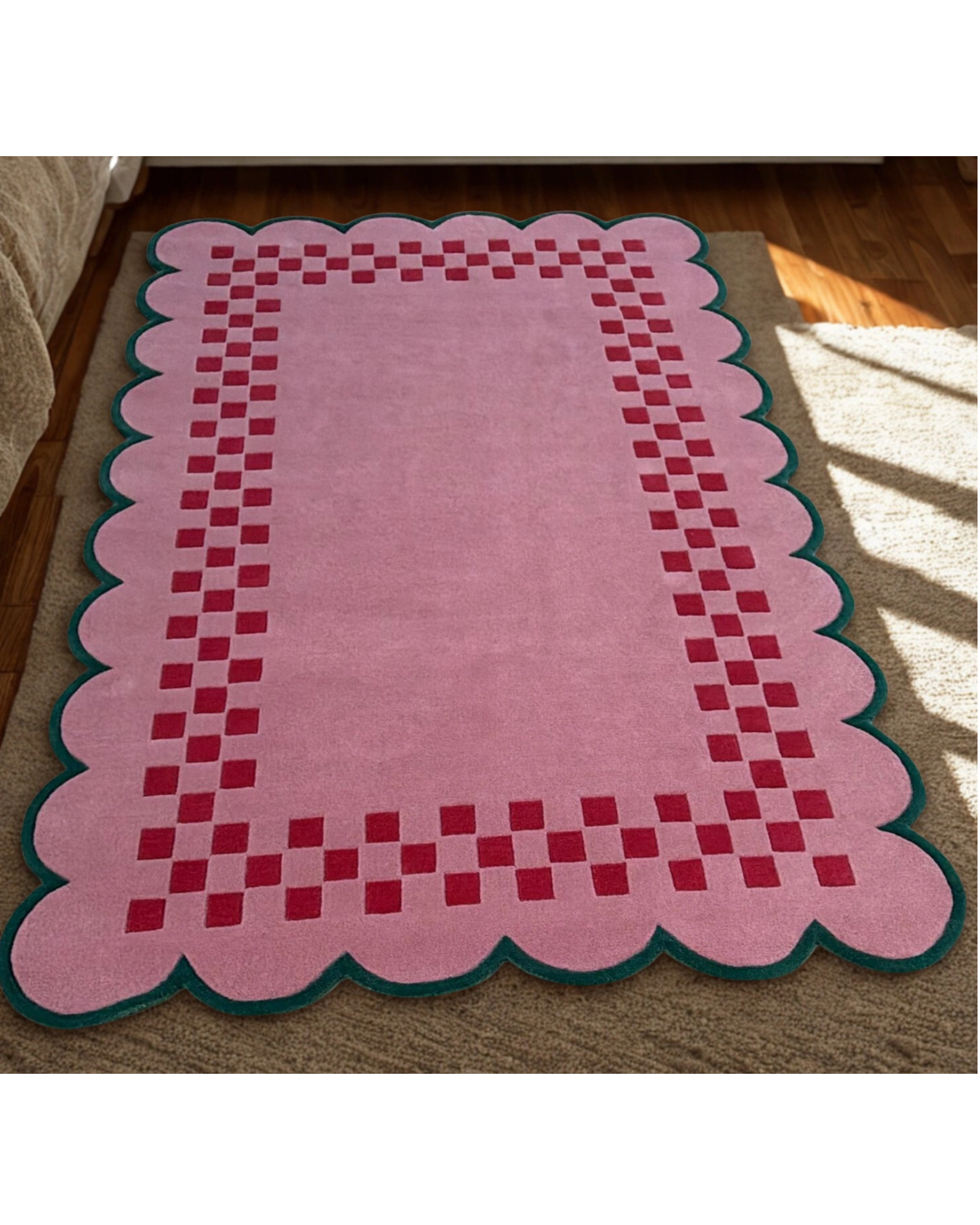 Soft pink scallop border rug with red checker pattern styled in a warm, sunlit room