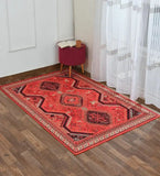 Luxurious red tribal patterned rug on wooden floor with maroon ottoman, book, and coffee cup near sheer white curtains