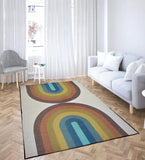 Modern living room with light gray sofa and chair, featuring a retro rainbow geometric arch rug on wooden floor