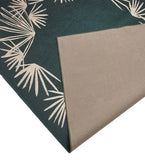 Handwoven luxury teal rug with beige palm leaf design, folded corner showing texture