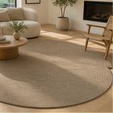 Round beige rug in a living room with a coffee table and chair.