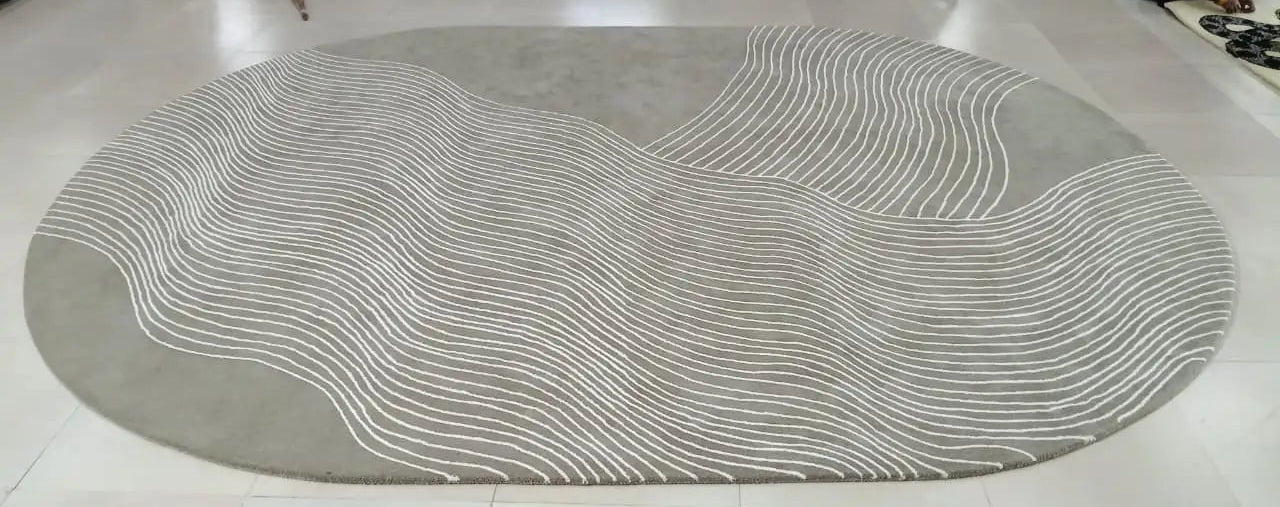 Round gray rug with wavy white lines on a white floor.