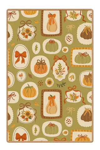 Harvest rug with pumpkins, bows, and leaves on green background.