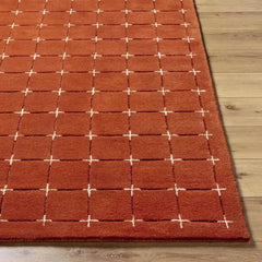 Red and cream hand-tufted rug with stitched square details.