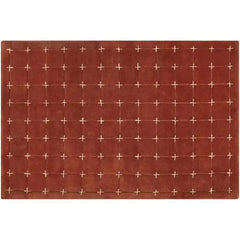 Modern geometric accent rug in red and white cross-stitch design.