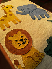 Children's rug with lion, elephant, and giraffe designs on a beige background