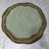 Round sage green and earthy tone handcrafted rug on white marble floor, luxury home decor
