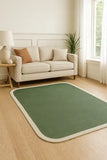 Modern living room with beige sofa, sage green rug with cream border, wooden flooring, and potted plant