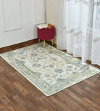 Shabby chic luxury handwoven rug with floral pattern on wood floor, next to red stool and sheer curtain