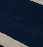 Minimalist solid midnight blue rug with light beige border on textured floor