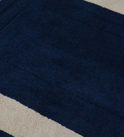Navy blue hand-tufted wool area rug with beige rectangular border.