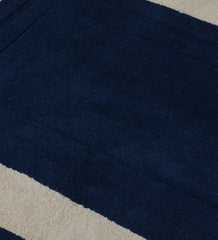 Navy blue hand-tufted wool area rug with beige rectangular border.