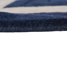 Close up and pile thickness of navy blue hand-tufted wool rug with beige rectangular border in a modern minimalist design.