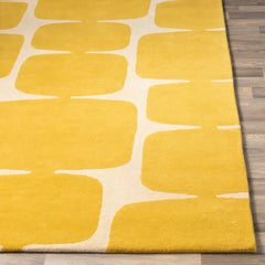 Yellow hand-tufted rug with abstract white pattern on wooden floor
