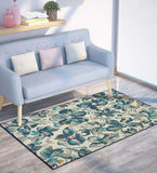 Teal floral watercolor style rug placed in a modern living room with light blue sofa and wooden floor