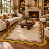A large scalloped area rug in cream with pink, olive green, and mustard yellow borders, styled in a cozy living room with a cream sectional sofa, wooden coffee table, and fireplace.