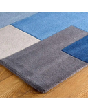 Modern handwoven rug with geometric pattern in blue, gray, and beige on wooden floor