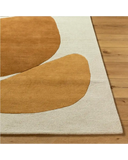 Modern handwoven rug with abstract tan shapes on cream background over wooden floor
