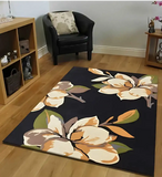 Living room with black floral area rug featuring large beige, orange, and green flowers on wooden floor