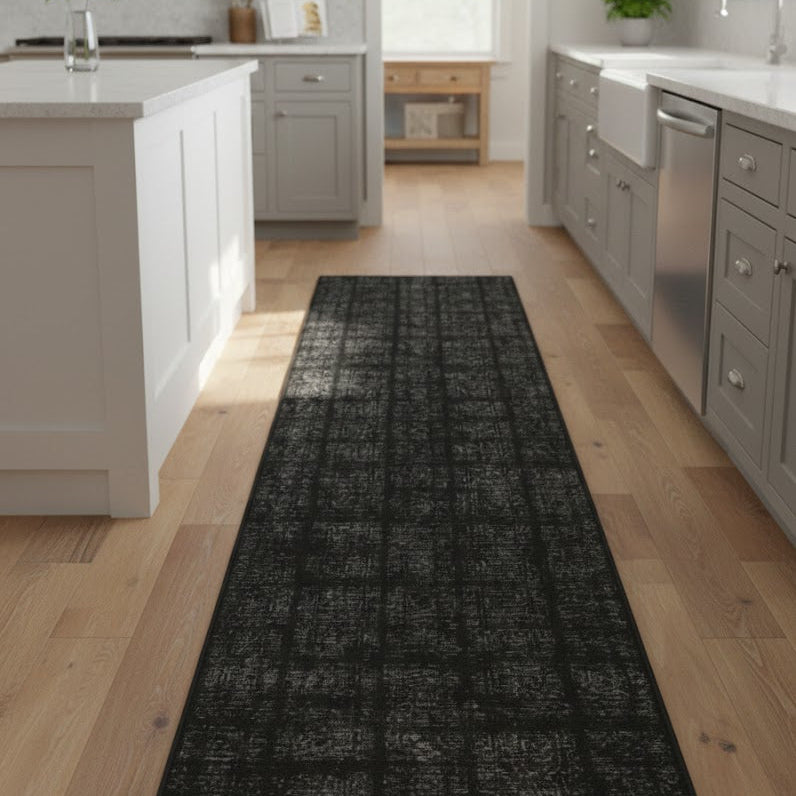 Black patterned rug on a wooden floor in a modern kitchen.