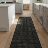Black patterned rug on a wooden floor in a modern kitchen.