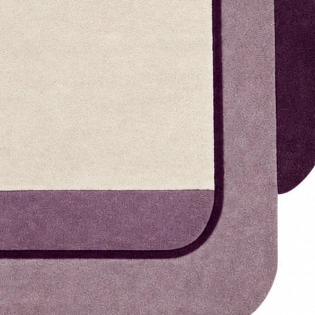 Close-up of hand-tufted purple and mauve wool rug with ivory geometric border for bedroom