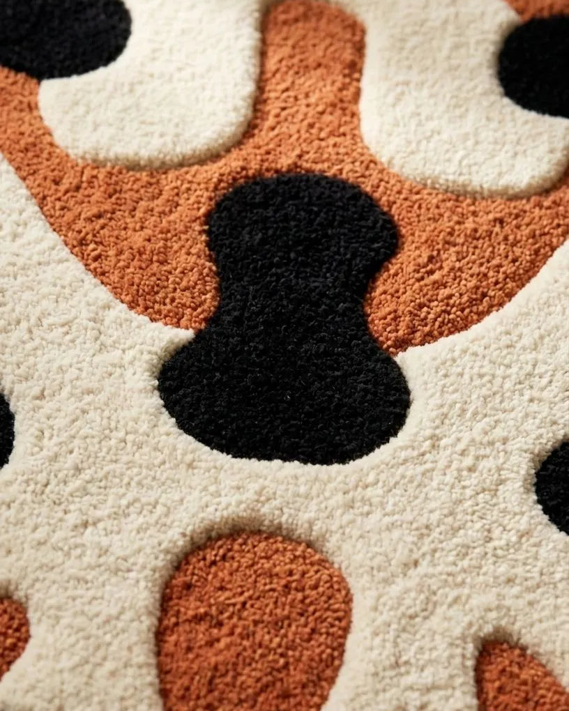 Close-up of a textured rug with black, orange, and white abstract pattern